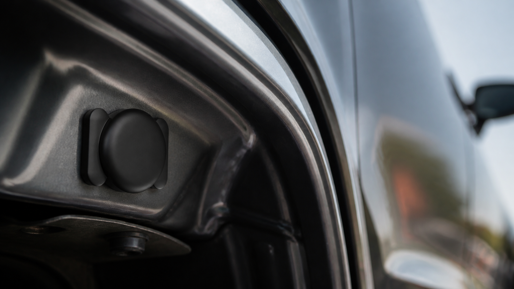 Black magnetic tracker attached to a hidden metal area of a car